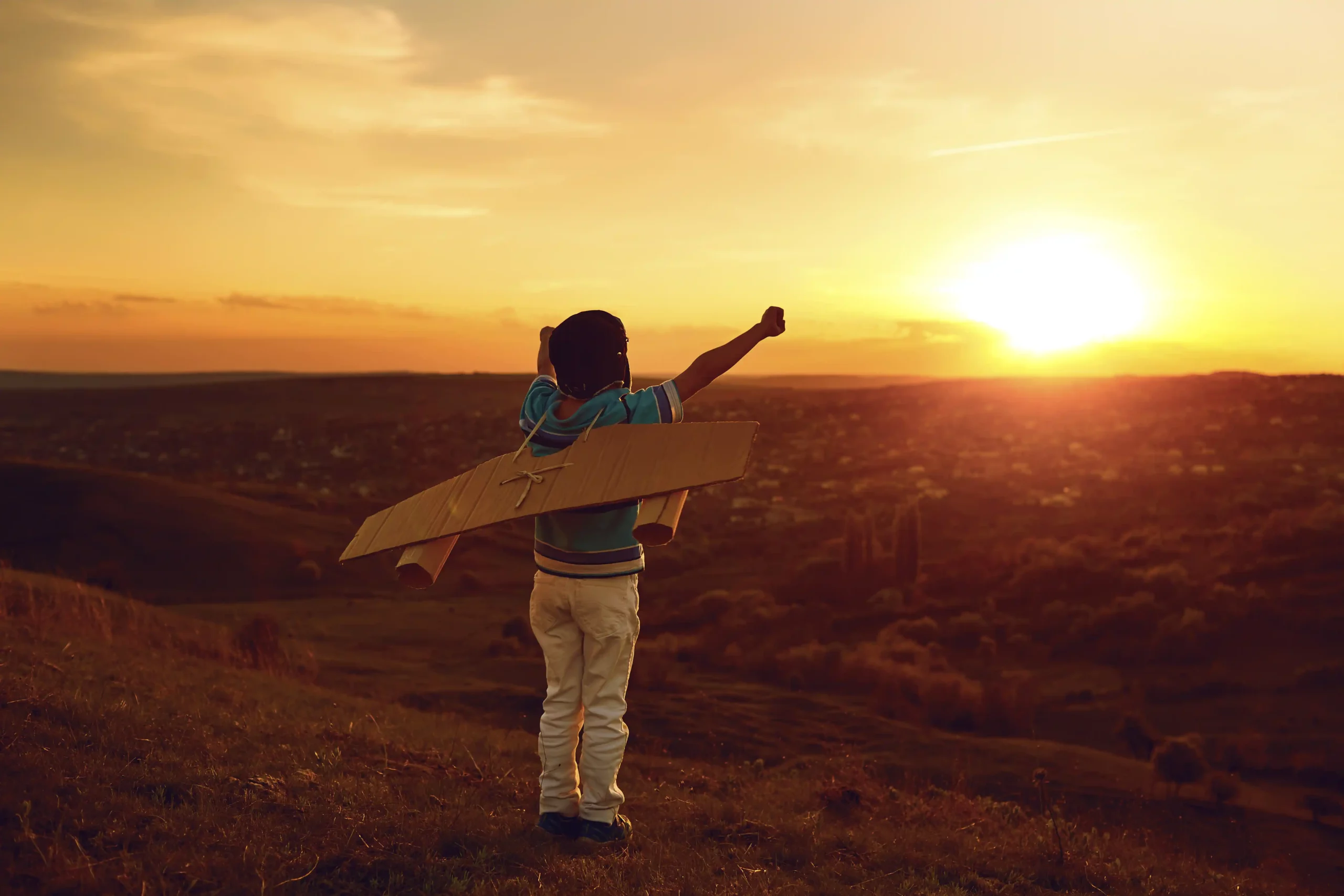 Ein Junge mit Flügeln aus Pappe reckt seine Arme der Sonne entgegen. Es symbolisiert, wie Start-ups ihre PR-Chancen nutzen.
