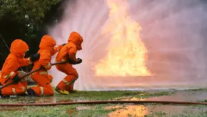 Drei Feuerwehrleute löschen gemeinsam einen Brand.